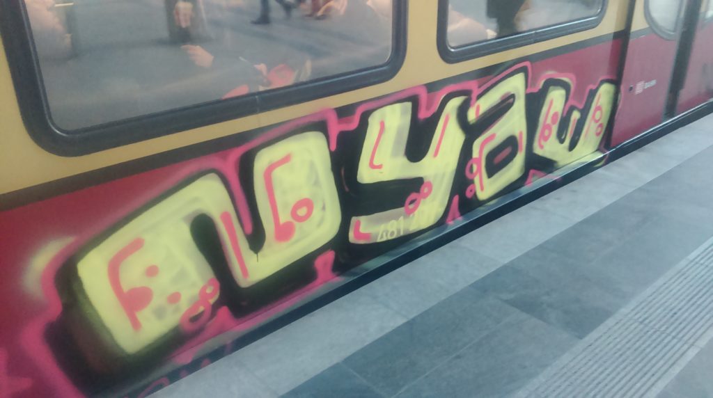NYAE-Graffiti on the Berlin train system "Ring-Bahn" with black shadows around yellow/white fillings