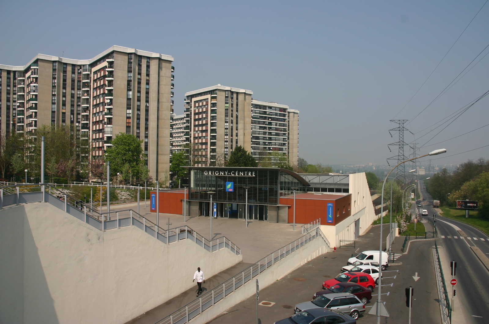 Plattenabuten ragen hitner dem bahnhof von grigny-Centre. Diese dicht besidelte Kommune im Departement der Essonne ist von skurpellosen Miethaien geplagt. Der Himmel ist blau und die Aufnahme älter.