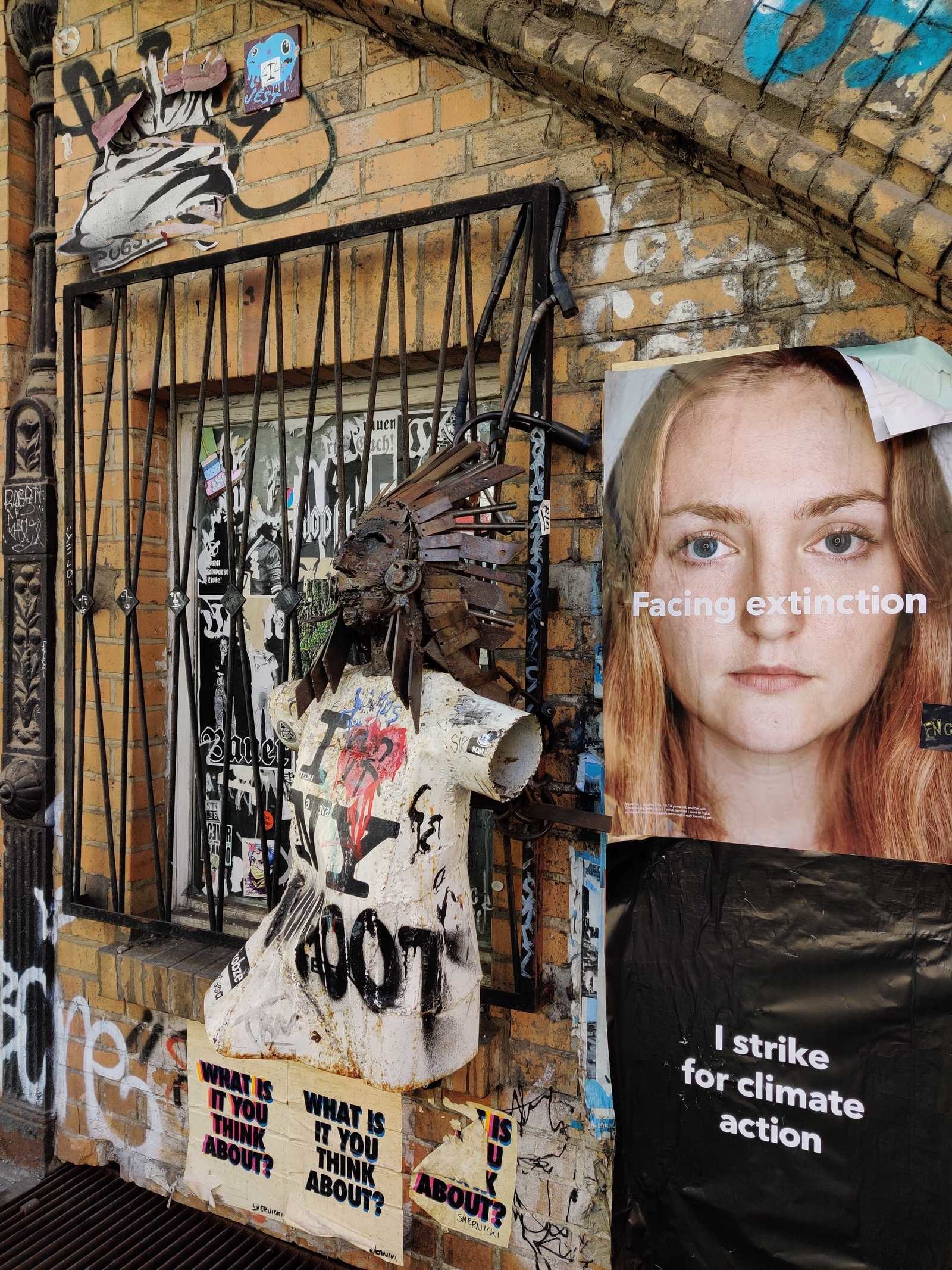 Pasted upon a Wall in Berlin: "Facing Extinction - I strike for climate action". Beside of the poster, a chaotic artsy wall in the typical flair of Germany's capital.